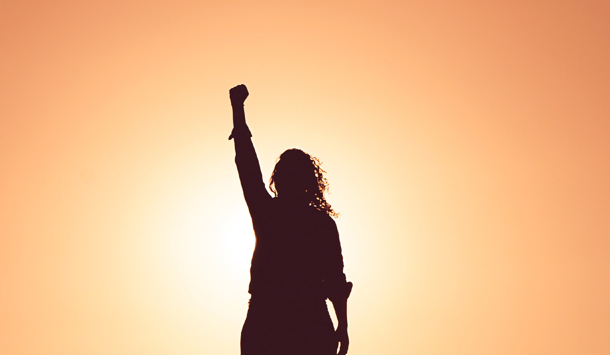 Silhouette of woman raising her fist
