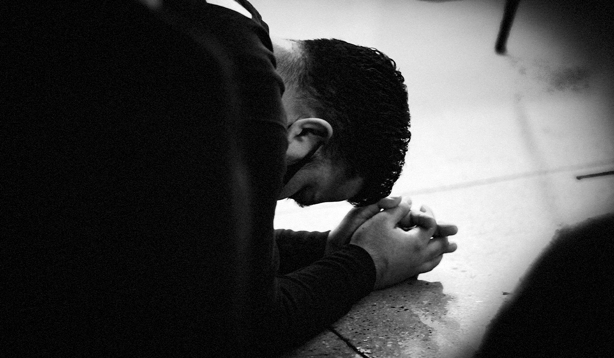 Man on the ground praying