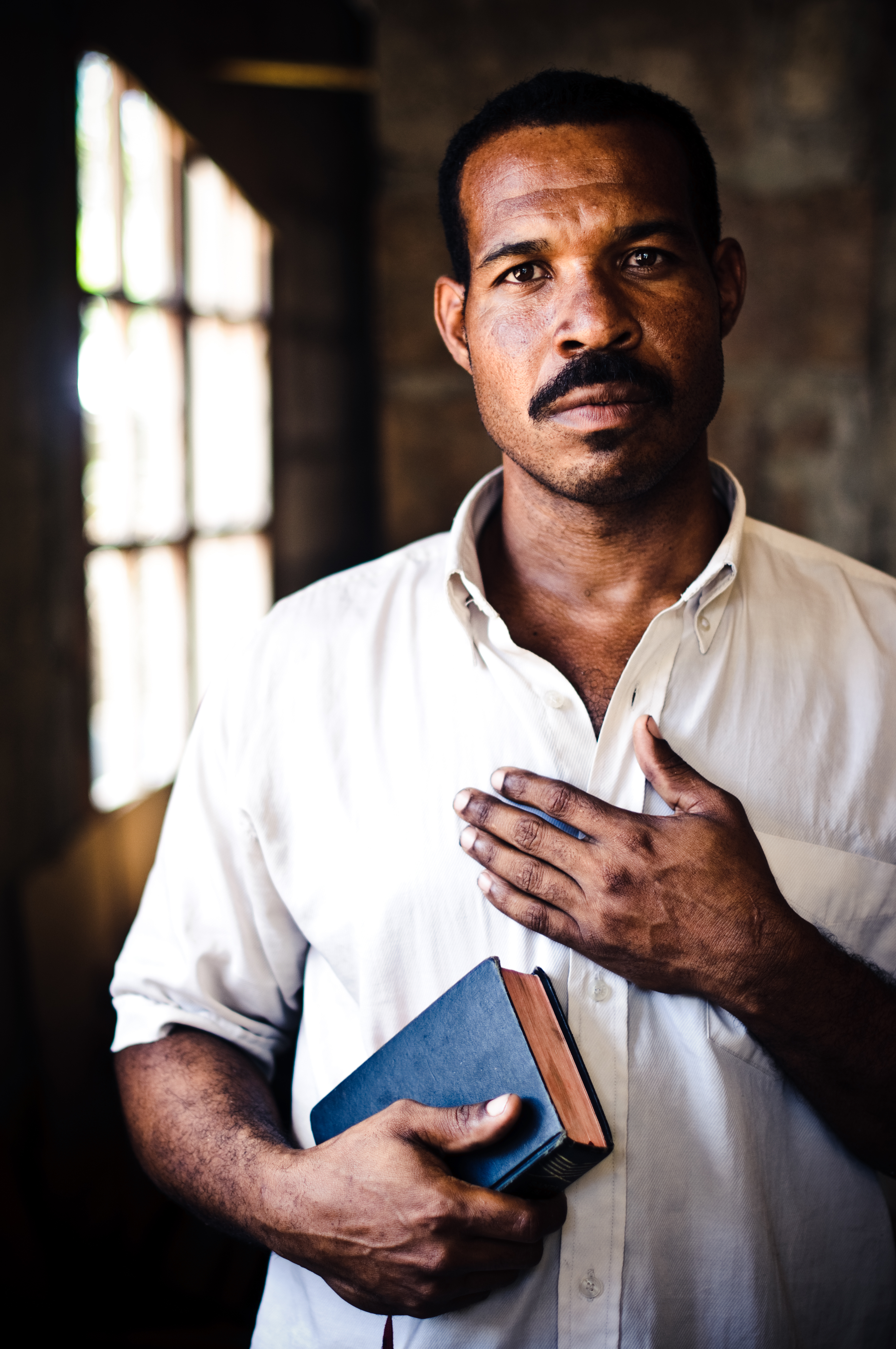 Man holding Bible with his hand on his chest