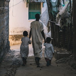 Adult and two children walking down an alley