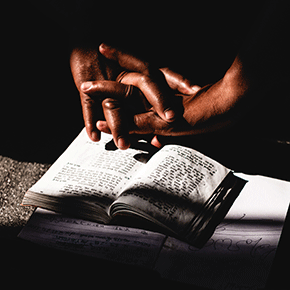 Hands folded on a book