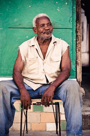 Latin man sitting on the sidewalk