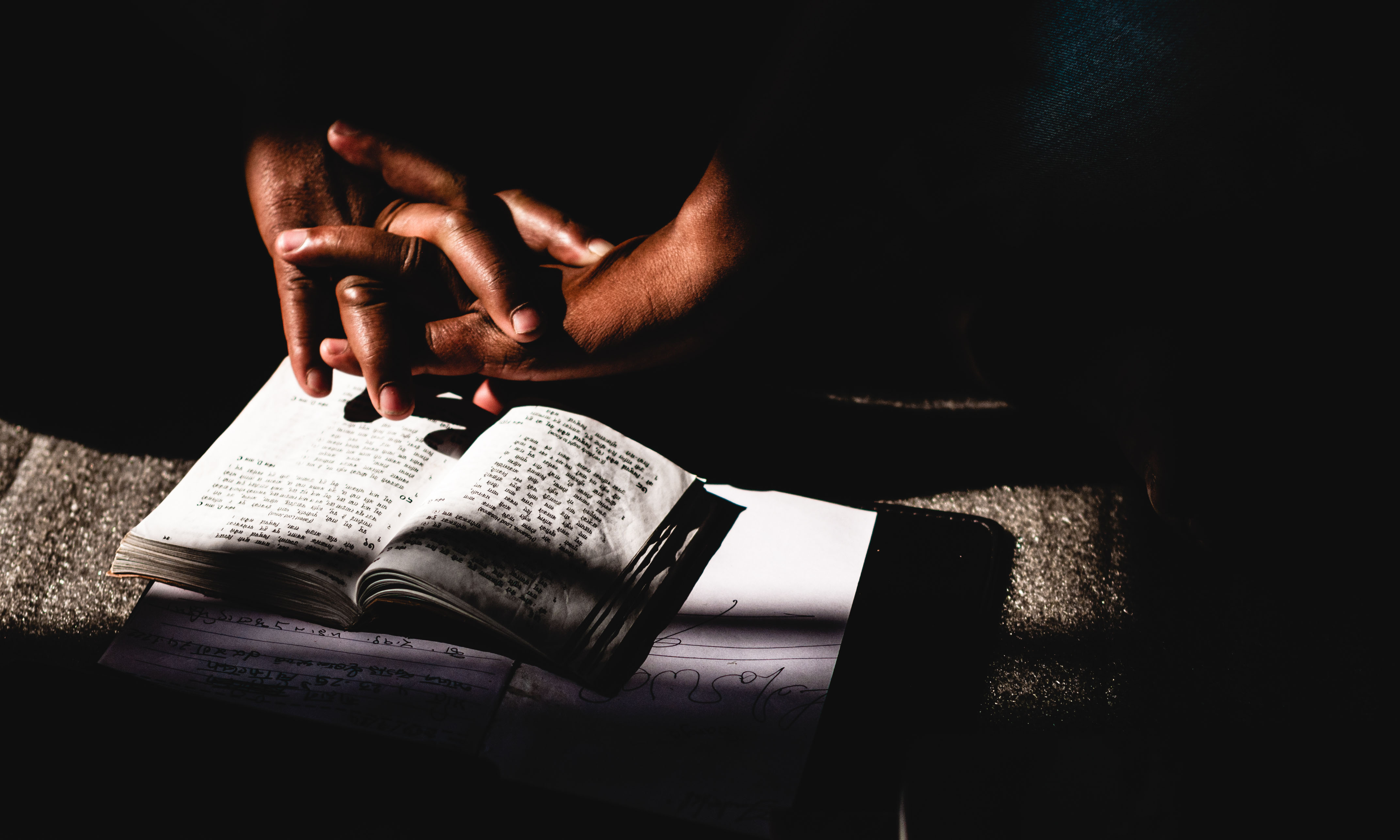 Hands folded on a Bible